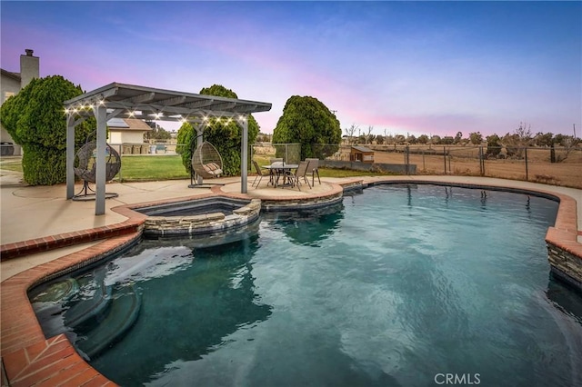 pool at dusk featuring a patio area, a pergola, a pool with connected hot tub, and fence