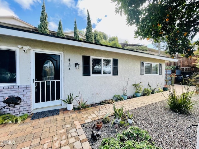 exterior space featuring stucco siding, fence, a patio area, and brick siding