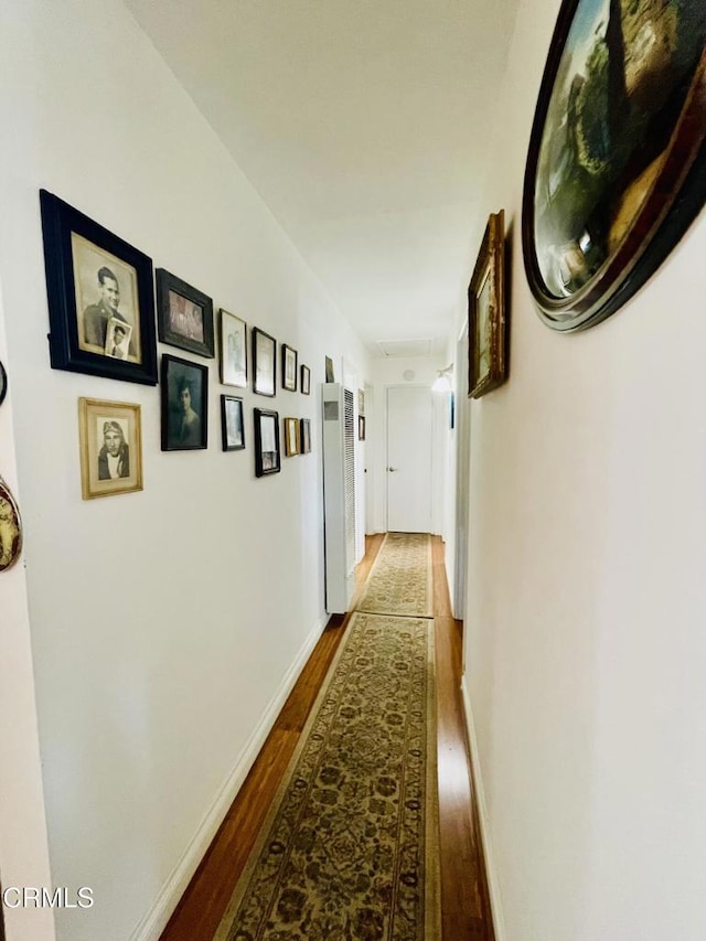 corridor with dark wood finished floors and baseboards