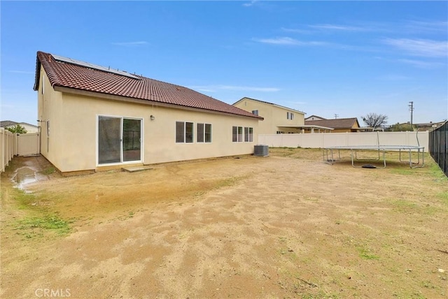 222 Garden Air Ct, Calimesa, CA 92320 - back of property with stucco siding, roof mounted solar panels, a trampoline, a fenced backyard, and a tiled roof