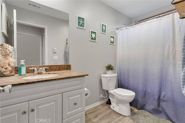 bathroom featuring visible vents, toilet, wood finished floors, baseboards, and vanity