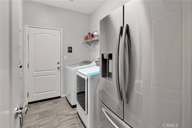 laundry room featuring baseboards, light wood-style floors, laundry area, and washing machine and clothes dryer