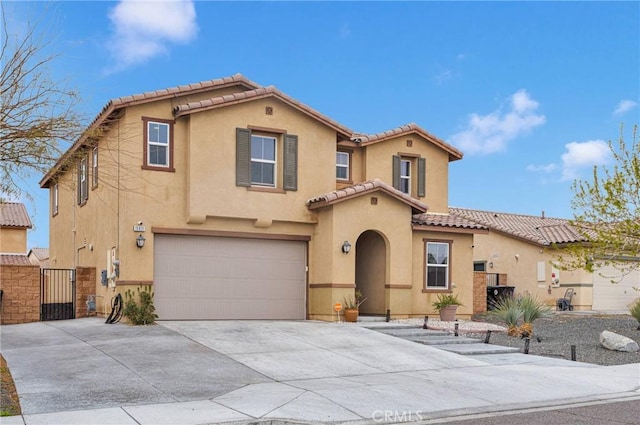 mediterranean / spanish-style house featuring stucco siding, driveway, a gate, an attached garage, and a tiled roof