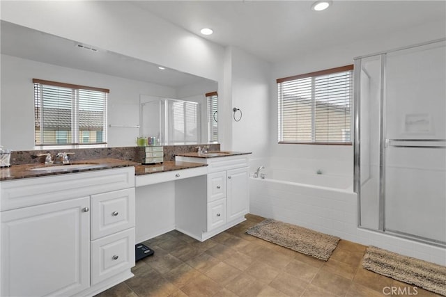 bathroom with double vanity, a healthy amount of sunlight, a stall shower, and a sink