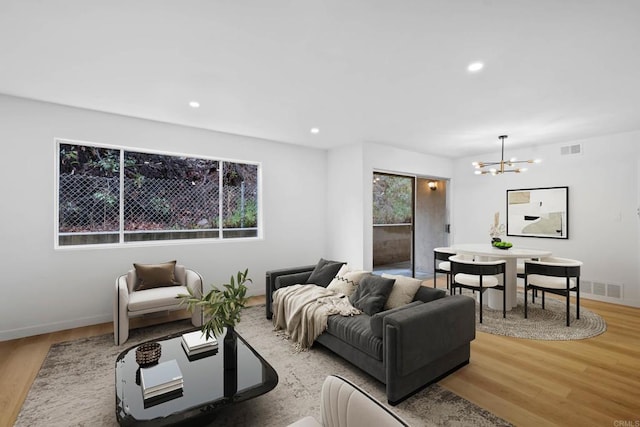 living room featuring light wood-style flooring, a notable chandelier, and visible vents