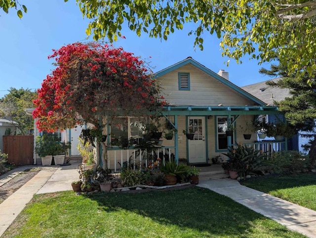 bungalow-style home featuring a porch, a front yard, and fence