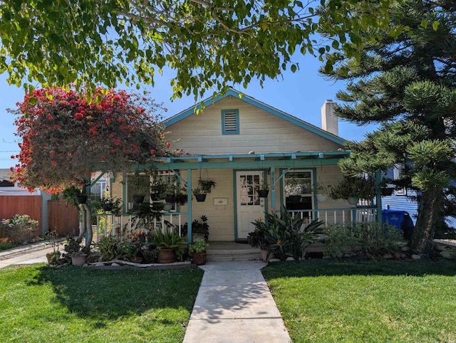 bungalow-style home with a front lawn, fence, covered porch, and a chimney