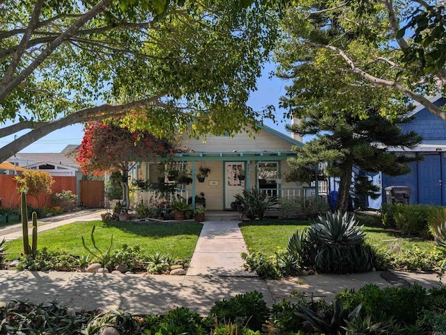 view of front of house featuring a front yard, fence, and covered porch