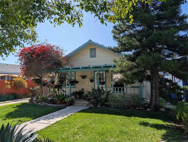 bungalow-style home featuring covered porch, a front lawn, and fence