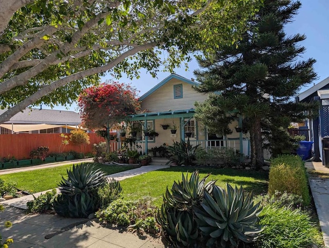 back of property featuring a porch, a yard, and fence