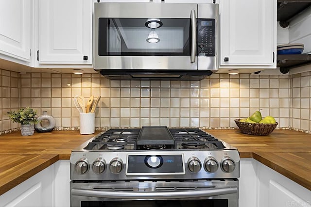 kitchen with white cabinetry, backsplash, appliances with stainless steel finishes, and butcher block counters