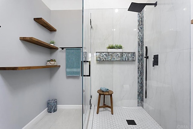 bathroom with a marble finish shower and baseboards