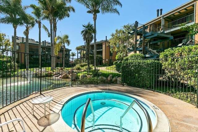 view of swimming pool featuring a community hot tub and fence