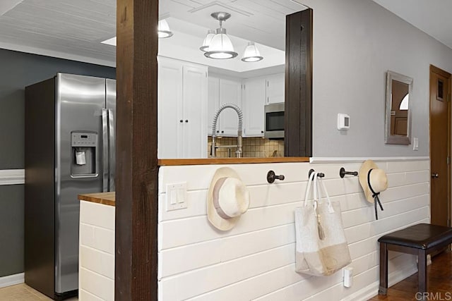 kitchen with decorative light fixtures, white cabinetry, stainless steel appliances, light wood-style floors, and wainscoting