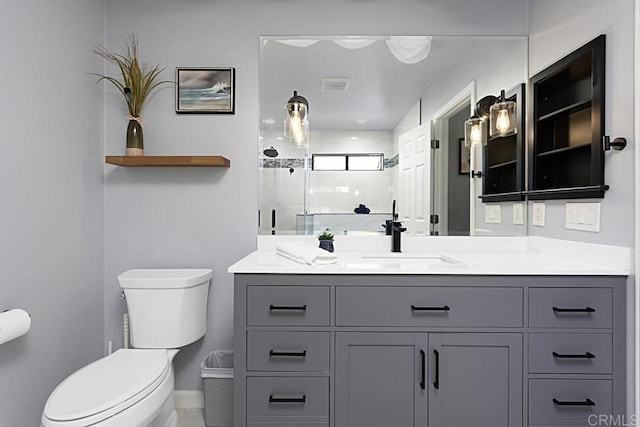 bathroom with visible vents, toilet, a shower stall, baseboards, and vanity