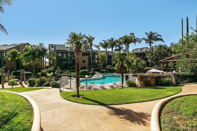 view of community featuring a lawn, a pool, and fence