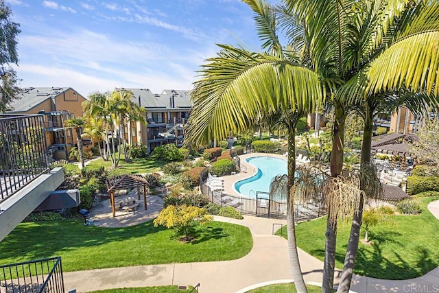 view of community with a patio, a lawn, a pool, and fence