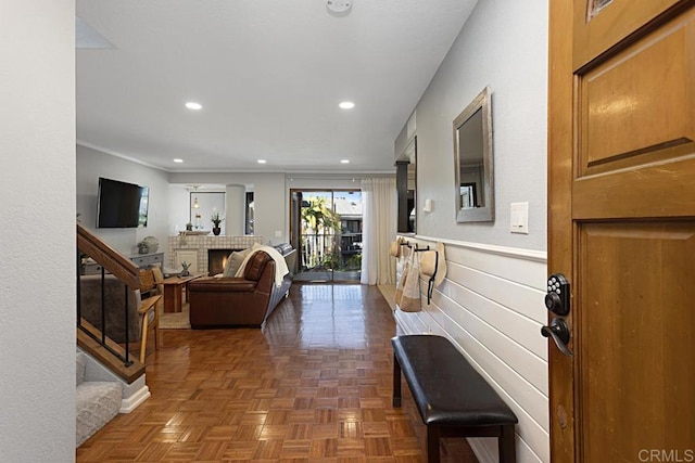 living room with stairway, a brick fireplace, recessed lighting, and a wainscoted wall