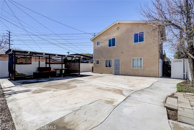back of property with a gate, stucco siding, and fence