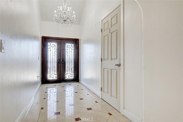 foyer featuring light tile patterned floors, french doors, baseboards, and a chandelier
