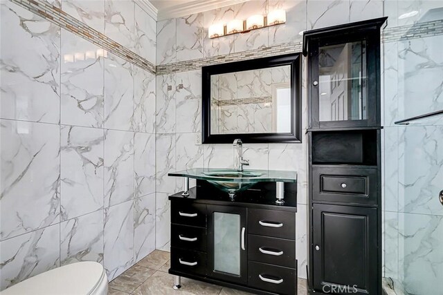 bathroom with toilet, vanity, tile walls, and ornamental molding