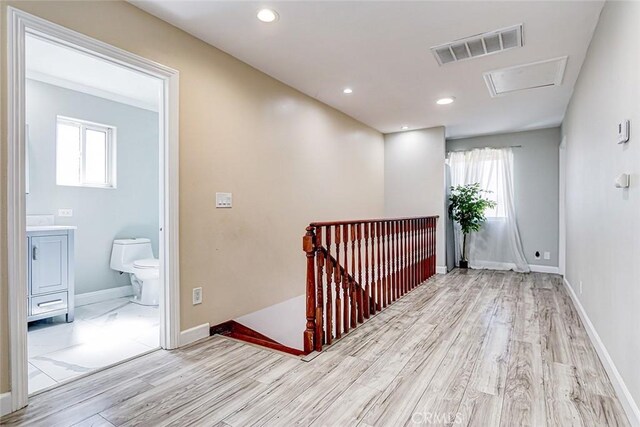 corridor with wood finished floors, visible vents, baseboards, recessed lighting, and an upstairs landing