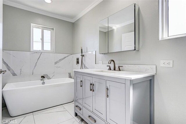 bathroom with marble finish floor, ornamental molding, tile walls, a soaking tub, and vanity