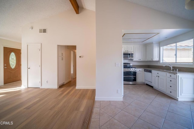 kitchen with visible vents, beam ceiling, a sink, appliances with stainless steel finishes, and white cabinetry