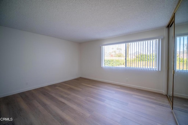 empty room featuring wood finished floors, baseboards, and a textured ceiling