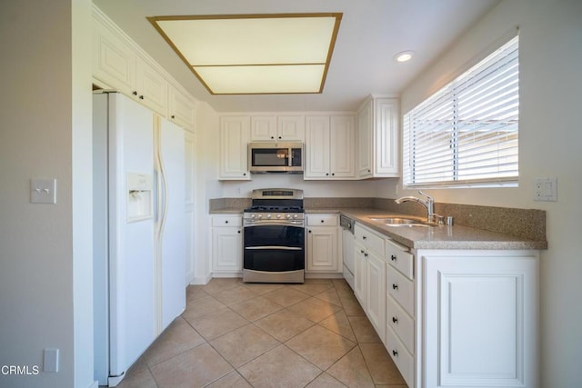kitchen featuring light tile patterned floors, appliances with stainless steel finishes, white cabinetry, and a sink
