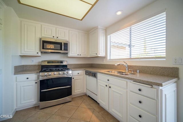 kitchen with a sink, white cabinetry, appliances with stainless steel finishes, and light tile patterned floors
