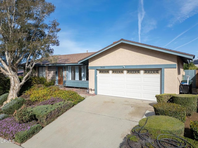 ranch-style house with concrete driveway, an attached garage, and stucco siding