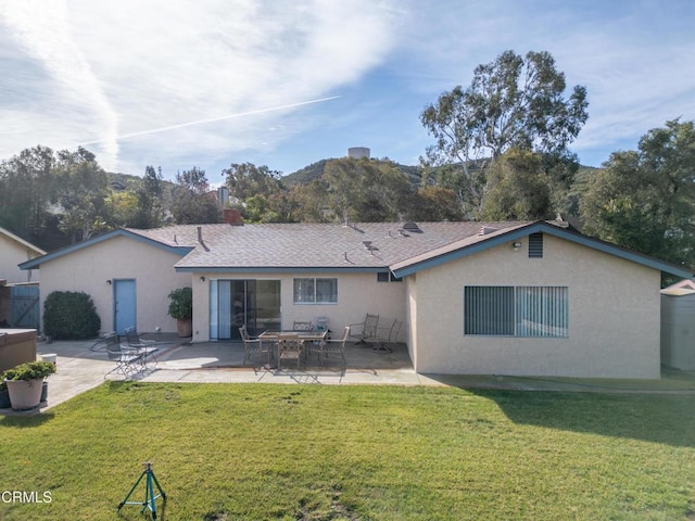 back of house featuring a patio area, a lawn, and stucco siding