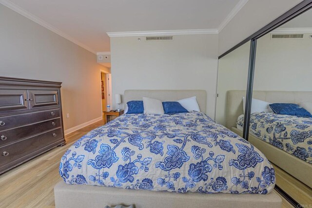 bedroom with light wood-style flooring, visible vents, a closet, and ornamental molding