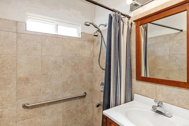 full bathroom featuring tiled shower and vanity