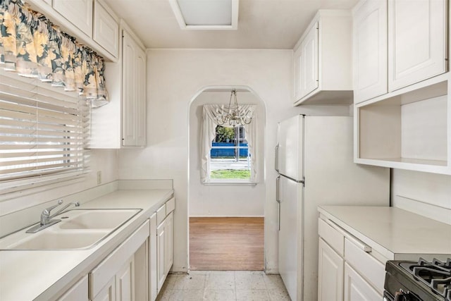 kitchen with white cabinetry, light countertops, and a sink