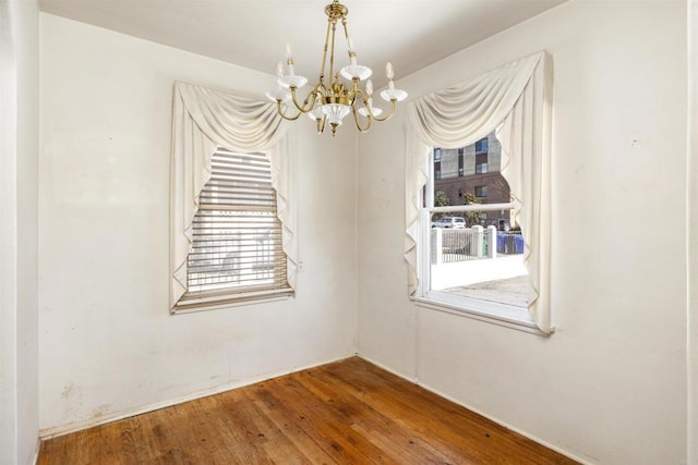 spare room featuring wood finished floors and a chandelier