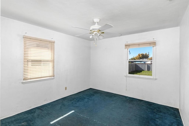 spare room featuring a ceiling fan and dark colored carpet