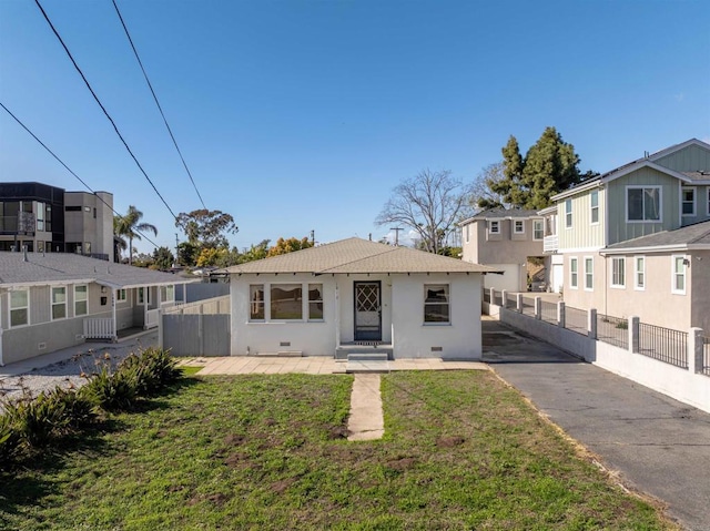 bungalow-style house featuring fence, a residential view, a front yard, and stucco siding