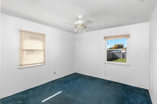 empty room with a ceiling fan and dark colored carpet