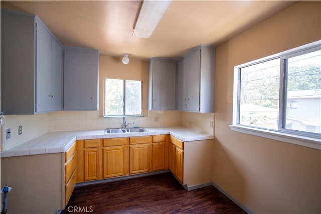 kitchen with a sink, tile counters, backsplash, and dark wood-style floors