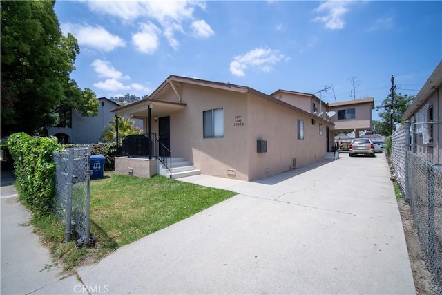view of front facade with a front yard, fence, driveway, stucco siding, and crawl space