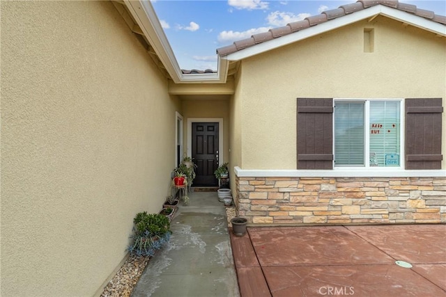 doorway to property featuring stucco siding and stone siding