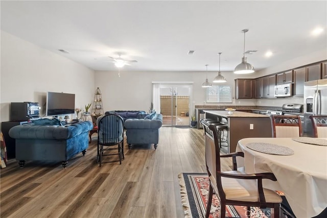 kitchen featuring a kitchen island, open floor plan, appliances with stainless steel finishes, dark brown cabinets, and ceiling fan