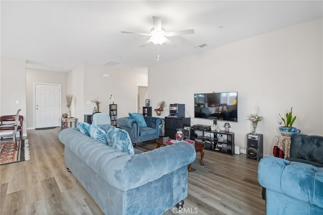 living area with visible vents, baseboards, light wood-style flooring, and a ceiling fan