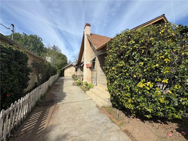 view of home's exterior featuring a chimney and fence