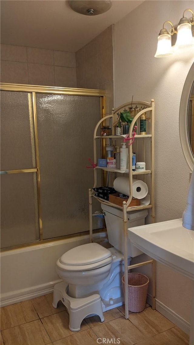 full bath featuring toilet and combined bath / shower with glass door