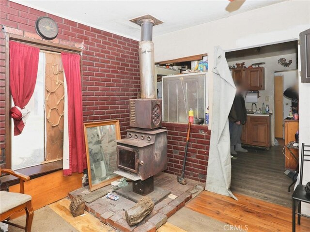3586 Halika St, Clearlake, CA 95422 - living room featuring a wood stove, wood finished floors, and brick wall