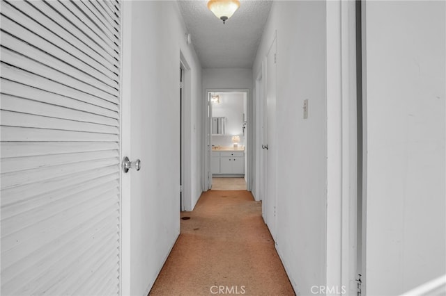 corridor featuring light colored carpet and a textured ceiling