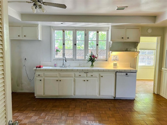 kitchen featuring backsplash, dishwasher, a sink, visible vents, and tile countertops
